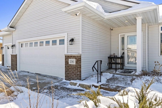 view of snow covered exterior with concrete driveway and an attached garage