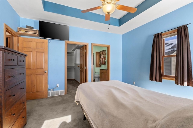 bedroom with a spacious closet, visible vents, carpet, a tray ceiling, and a closet