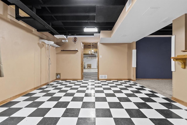 finished below grade area featuring tile patterned floors, visible vents, and baseboards