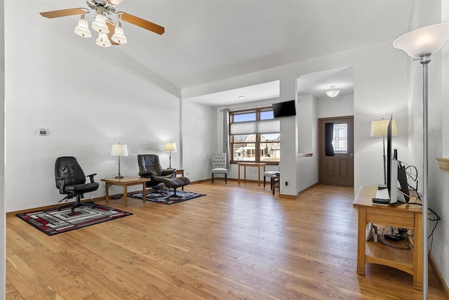 living area with light wood finished floors, baseboards, lofted ceiling, and ceiling fan