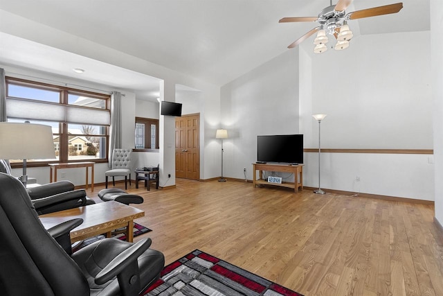 living room featuring light wood-style flooring, baseboards, high vaulted ceiling, and ceiling fan