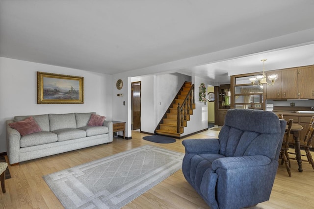 living room featuring stairway, light wood-style flooring, and a chandelier