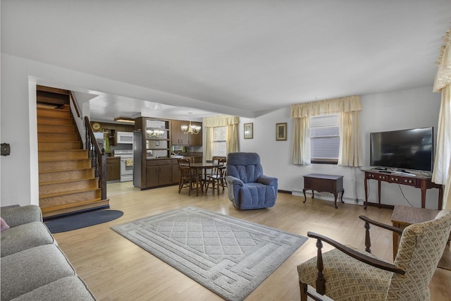 living area with a chandelier, light wood-style flooring, and stairs