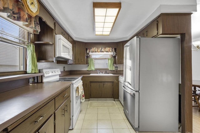 kitchen with a sink, light tile patterned floors, a wealth of natural light, white appliances, and open shelves