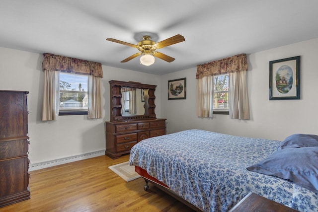 bedroom with ceiling fan, baseboards, baseboard heating, and light wood-style flooring