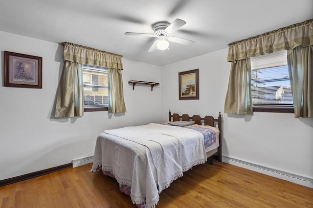 bedroom featuring a baseboard radiator, baseboards, and wood finished floors