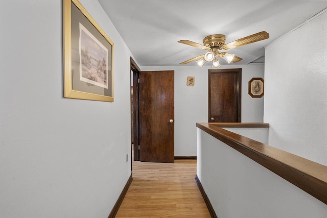 corridor featuring an upstairs landing, light wood-style floors, and baseboards