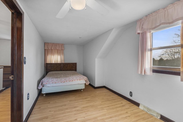 bedroom featuring ceiling fan, visible vents, baseboards, and light wood-style flooring