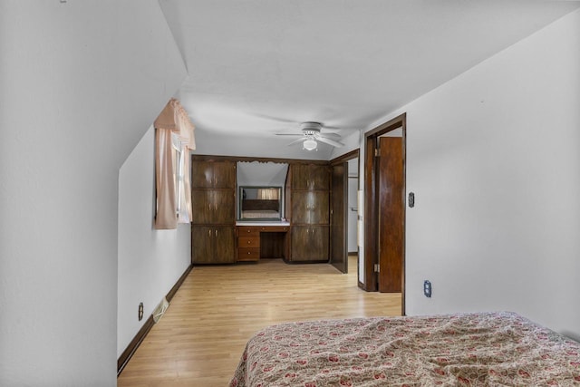 bedroom with visible vents, baseboards, light wood-style flooring, ceiling fan, and built in desk