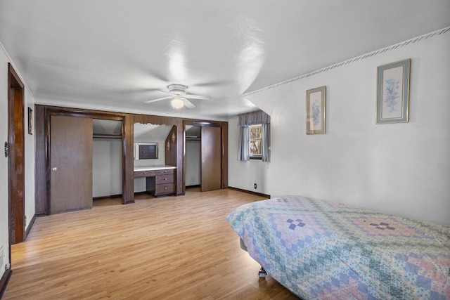 bedroom featuring light wood finished floors, baseboards, two closets, and ceiling fan