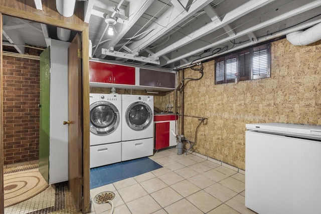 laundry room with light tile patterned floors, laundry area, brick wall, and separate washer and dryer