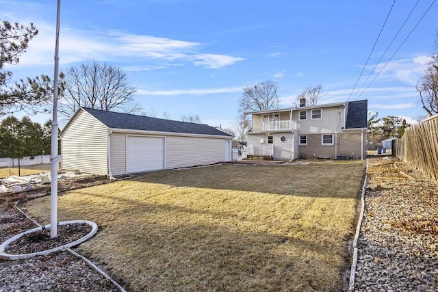 view of yard with a garage, a balcony, an outdoor structure, and fence