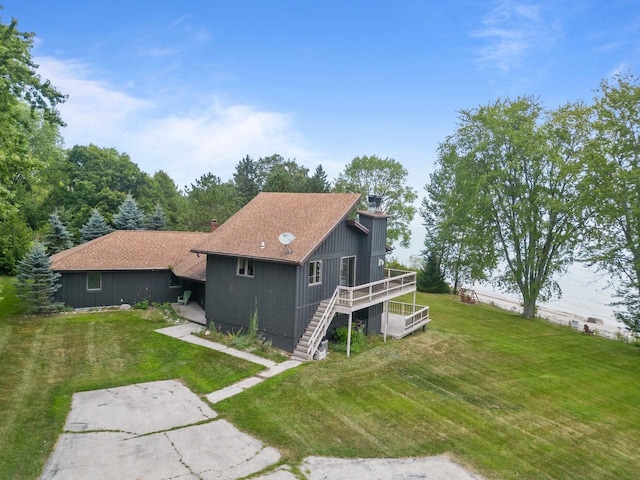 rear view of house featuring a deck, a chimney, stairs, and a yard