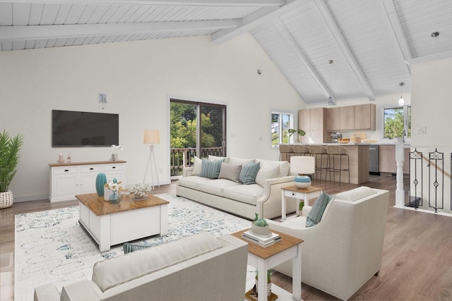 living area with beamed ceiling, a healthy amount of sunlight, light wood-type flooring, and high vaulted ceiling