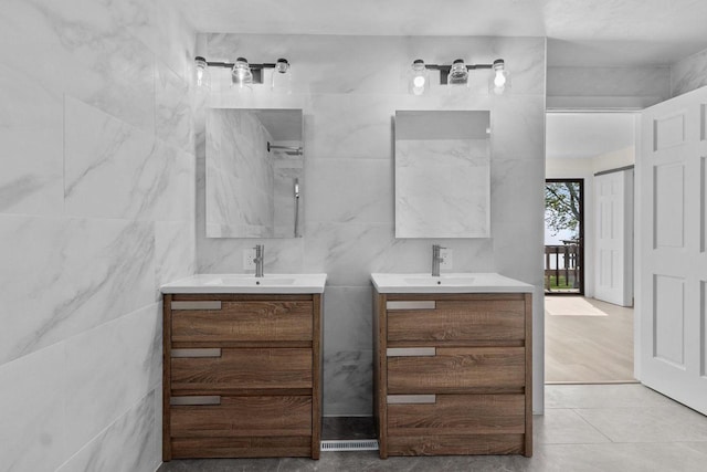 full bathroom featuring tile walls, two vanities, and a sink