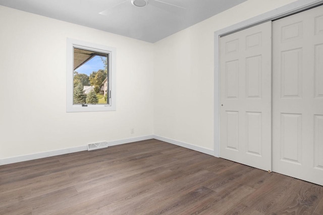 unfurnished bedroom featuring visible vents, wood finished floors, a closet, baseboards, and ceiling fan