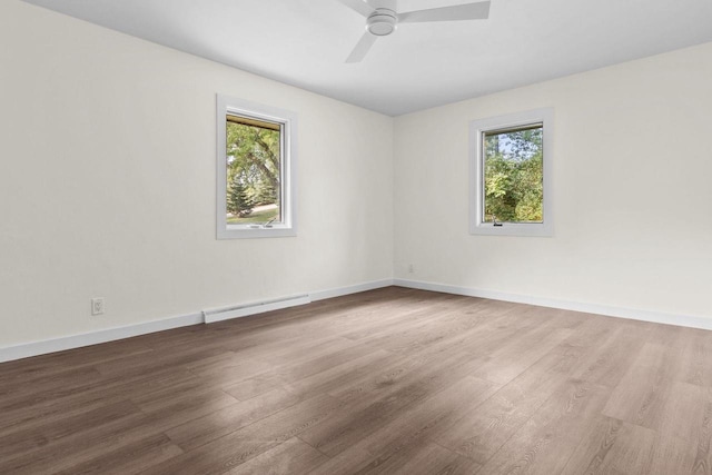 spare room with a ceiling fan, wood finished floors, baseboards, and baseboard heating