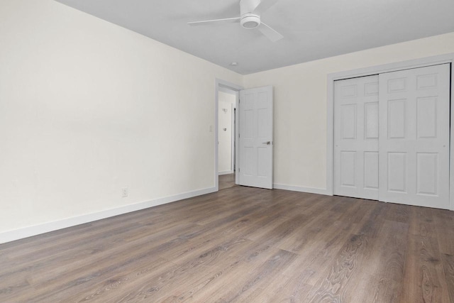 unfurnished bedroom with a ceiling fan, wood finished floors, baseboards, and a closet