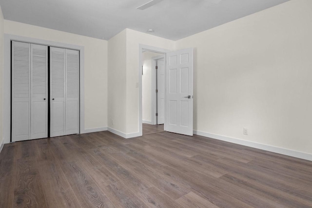 unfurnished bedroom with wood finished floors, baseboards, and a closet