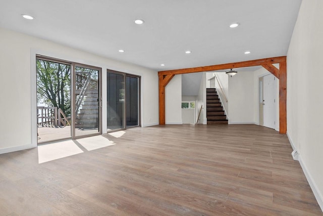 unfurnished living room featuring recessed lighting, light wood-style flooring, and stairs