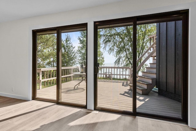 doorway featuring a water view, baseboards, and wood finished floors