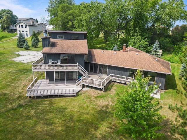 back of house with a yard, roof with shingles, and a deck