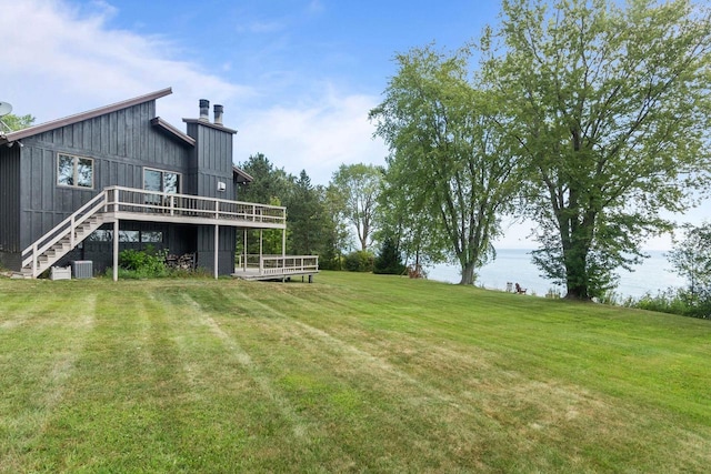 view of yard with a deck with water view, cooling unit, and stairs