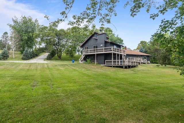 rear view of property with a yard, a deck, and a chimney