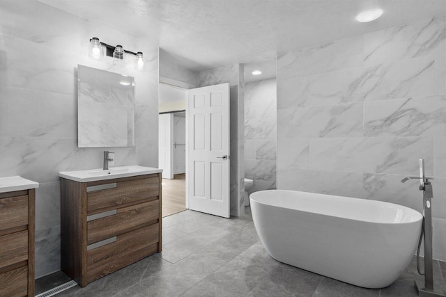 bathroom featuring a soaking tub, vanity, and tile walls