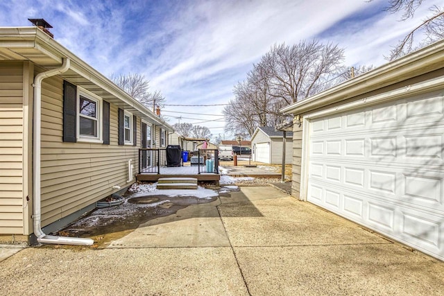 view of side of property with a garage, a deck, and an outdoor structure