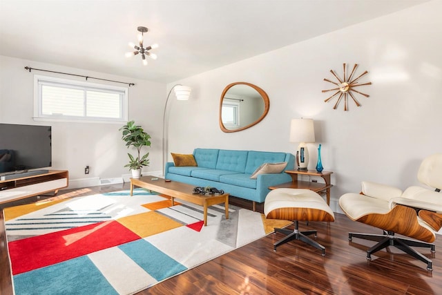 living room with a notable chandelier, visible vents, baseboards, and wood finished floors