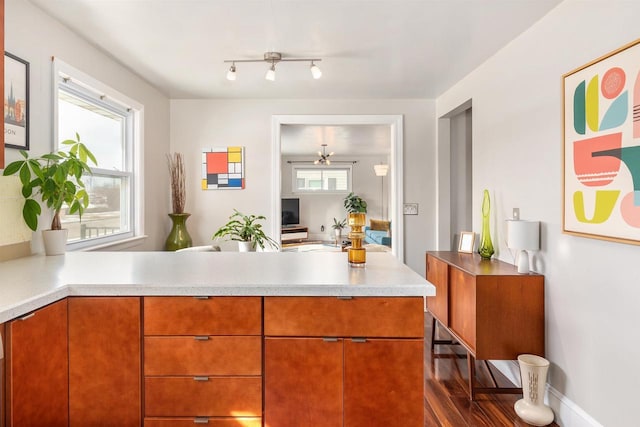 kitchen with light countertops, brown cabinetry, plenty of natural light, and a peninsula