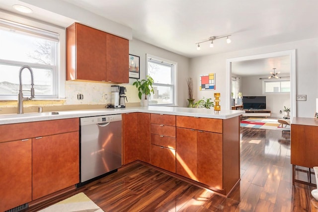 kitchen with dishwasher, light countertops, a peninsula, and a sink