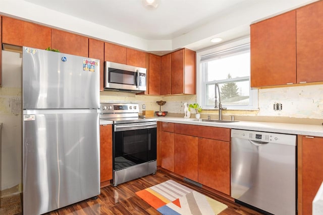 kitchen with a sink, appliances with stainless steel finishes, light countertops, decorative backsplash, and dark wood-style flooring