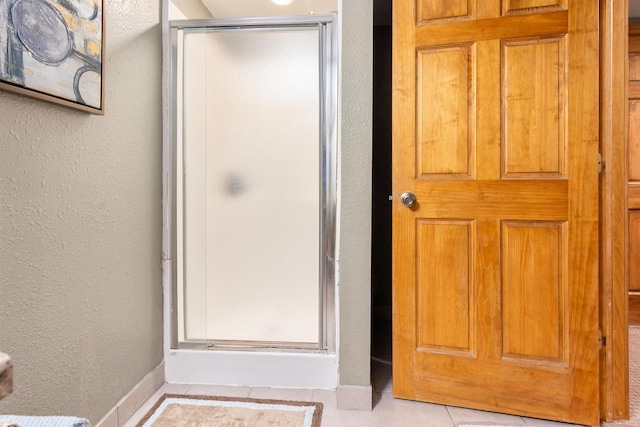 full bath with a textured wall, a stall shower, and tile patterned flooring