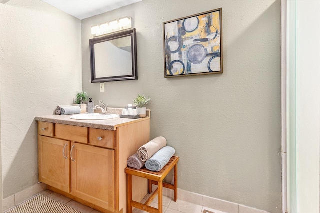 bathroom with tile patterned floors, baseboards, vanity, and a textured wall