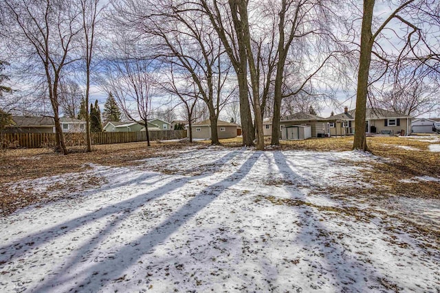 yard layered in snow with fence and a residential view