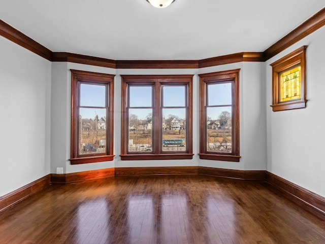 unfurnished room with dark wood finished floors, baseboards, and ornamental molding