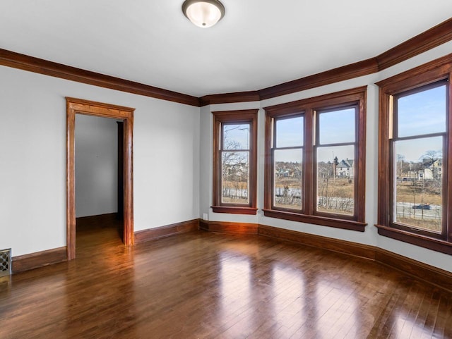 spare room with crown molding, baseboards, and dark wood-style flooring