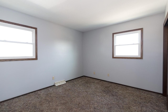 carpeted empty room featuring visible vents, a healthy amount of sunlight, and baseboards