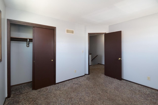 unfurnished bedroom featuring a closet, visible vents, baseboards, and dark colored carpet