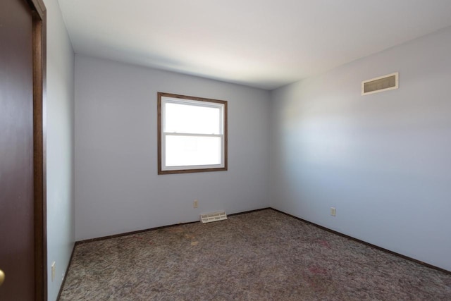 carpeted spare room featuring visible vents and baseboards