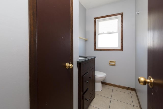 half bath with vanity, tile patterned floors, toilet, and baseboards