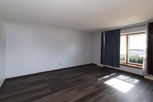 empty room with dark wood finished floors and baseboards