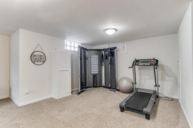 exercise room with carpet, baseboards, and a textured ceiling