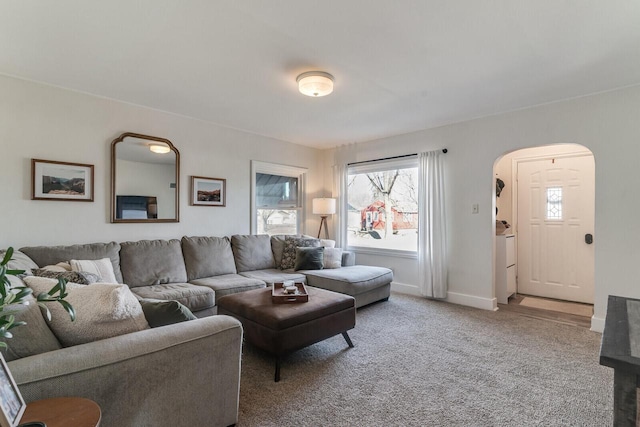 carpeted living area featuring baseboards and arched walkways