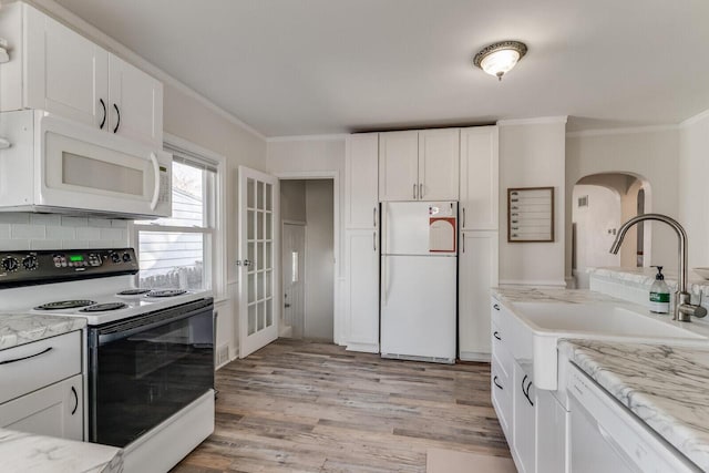 kitchen featuring a sink, white appliances, light wood-style flooring, and crown molding