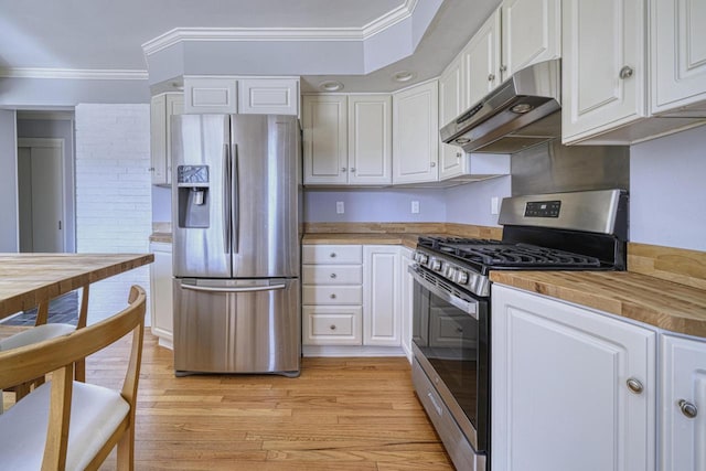 kitchen with under cabinet range hood, ornamental molding, stainless steel appliances, white cabinetry, and wood counters