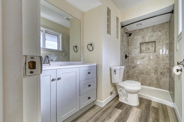 full bathroom featuring vanity, toilet, wood finished floors, and tiled shower