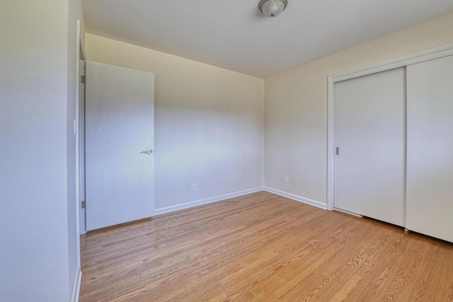 unfurnished bedroom with a closet, baseboards, and light wood-style flooring